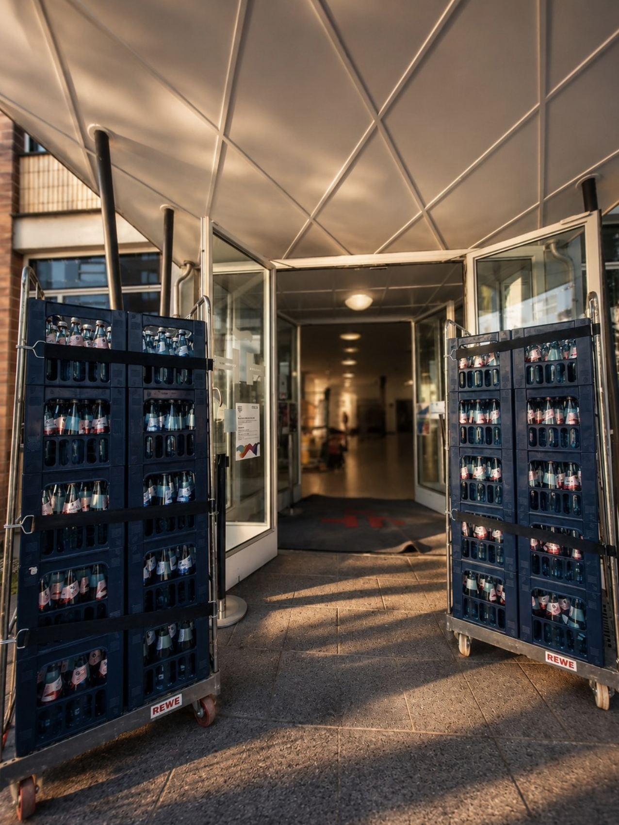 Getränke Grossmann office delivery with Elisabethen water crates on transport trolleys at a building entrance in Frankfurt